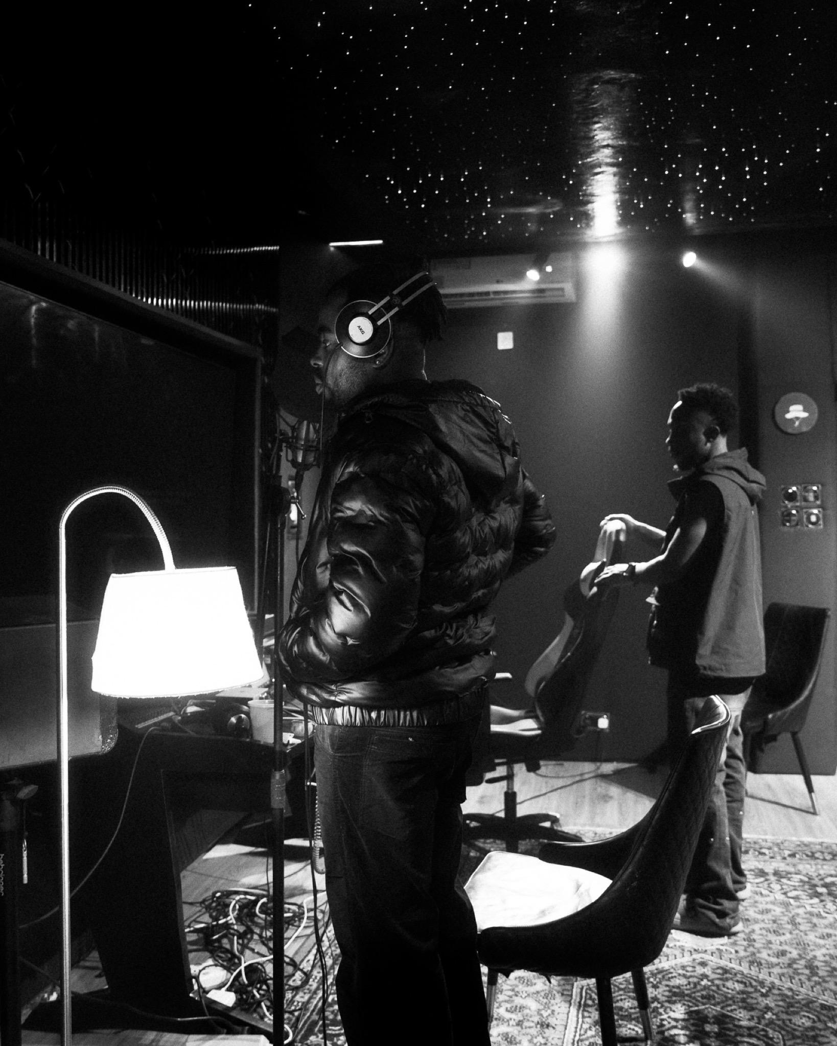 DERAA standing in the studio in headphones, mid-session