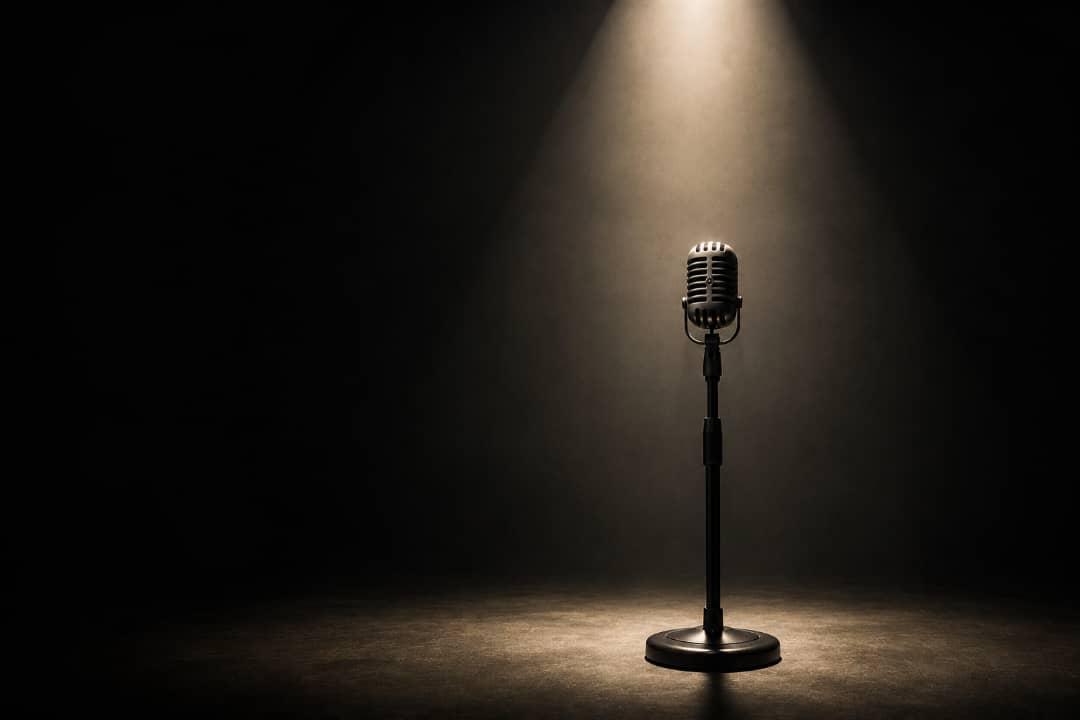 A microphone on a stage under a single spotlight